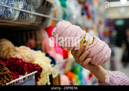 Nahaufnahme einer Frau, die Garn für handgeschöpftes Stricken in einem Handarbeitsgeschäft wählt. Nähwerkstatt. Stockfoto