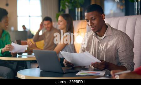 Geschäftsmann, Der Im Modernen Büro Mit Informeller Sitzecke Am Laptop Arbeitet Stockfoto