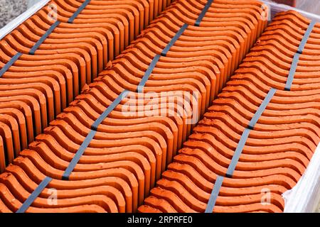 Neue rotbraune, auf dem Dach gebrannte keramische Tonfliesen, die in Reihen verpackt und an eine Restaurierungseinrichtung geliefert werden Stockfoto