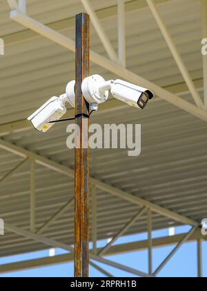 Metallmast mit zwei Überwachungskameras für Überwachungskameras im Freien auf einer unfertigen Baustelle Stockfoto