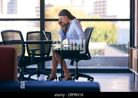 Gestresste, Reife Geschäftsfrau, Die Am Laptop Arbeitet Und Am Sitzungssaal Sitzt Stockfoto