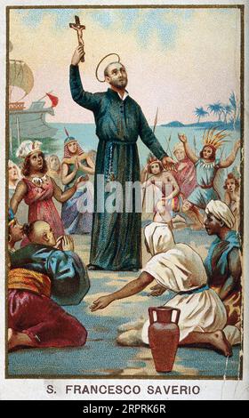 Der Heilige Franz Xavier, 1506–1552, hält ein Kruzifix, umgeben von asiatischen und afrikanischen Menschen, die vor ihm knieten, Meer und ein Schiff im Hintergrund. Farblithographie c1898. Stockfoto