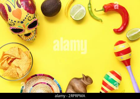 Rahmen aus mexikanischem Essen, Maracas, Sombrero und Zuckerschädel auf gelbem Hintergrund Stockfoto