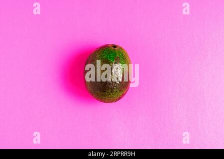 Überreife, verdorbene Avocado auf rosafarbenem Hintergrund. Stockfoto