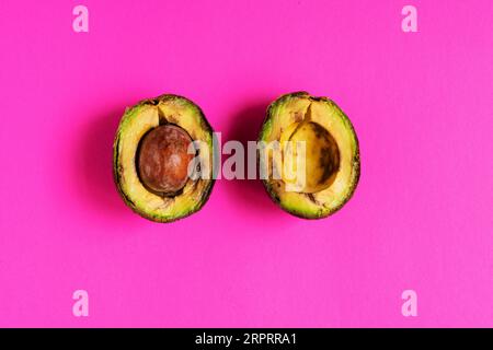 Überreife, verdorbene Avocado auf rosafarbenem Hintergrund. Stockfoto