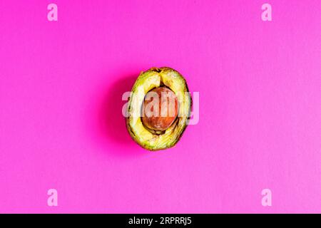 Überreife, verdorbene Avocado auf rosafarbenem Hintergrund. Stockfoto