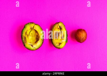 Überreife, verdorbene Avocado auf rosafarbenem Hintergrund. Stockfoto