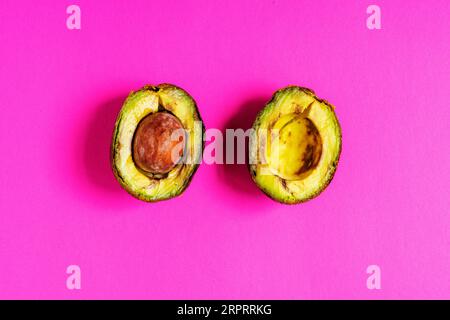 Überreife, verdorbene Avocado auf rosafarbenem Hintergrund. Stockfoto