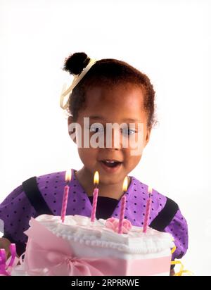 GEBURTSTAGSKINDER MÄDCHEN HAPPY Cake Kerzen 4 Jahre altes süßes hübsches britisches afrikanisches Afro Karibik Mädchen feiert mit ihrem besonderen Geburtstagskuchen Stockfoto