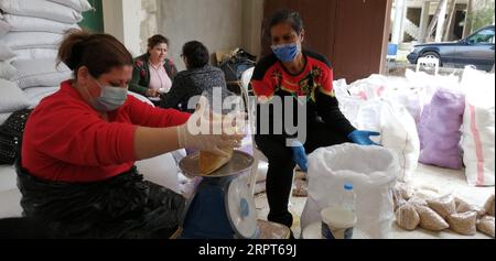 200411 -- TRIPOLI, 11. April 2020 Xinhua -- Freiwillige, die Masken und Handschuhe tragen, wiegen und Sackkörner, die am 11. April 2020 an die armen Menschen im nördlichen libanesischen Akkar-Gouvernement verteilt werden sollen. Die Zahl der COVID-19-Infektionen im Libanon stieg am Samstag um 10 auf 619 Fälle, während die Zahl der Todesopfer bei 20 blieb. Foto: Khalid/Xinhua LEBANON-TRIPOLI-FOOD AID-COVID-19 PUBLICATIONxNOTxINxCHN Stockfoto