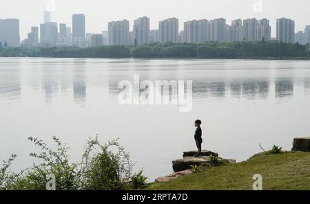 200413 -- WUHAN, 13. April 2020 -- Ein Junge beobachtet den Blick am See am Donghu Greenway in Wuhan, zentralchinesische Provinz Hubei, 13. April 2020. Als die Coronavirus-Epidemie abnimmt, kommen immer mehr Menschen nach Donghu Greenway, um den Frühling zu genießen. CHINA-HUBEI-WUHAN-GREENWAY CN ChengxMin PUBLICATIONxNOTxINxCHN Stockfoto