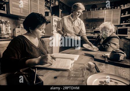 Familie weibliche Generationen zusammen 1990er Jahre drei weibliche 3 Generationen leben zu Hause zusammen, mit älteren Großmutter, Mutter und Enkelin treffen sich zum Essen in ihrer Hausküche Stockfoto