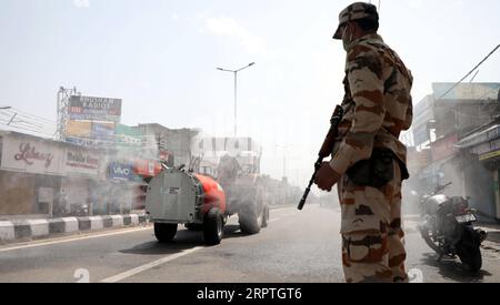 200415 -- JAMMU, 15. April 2020 -- Ein paramilitärischer Soldat steht Wache, während Ein kommunaler Arbeiter Ein Desinfektionsmittel auf einem Marktplatz gegen COVID-19 während der Abriegelung als Vorsichtsmaßnahme in Jammu, der Winterhauptstadt des von Indien kontrollierten Kaschmirs, am 15. April 2020 spritzt. STR/Xinhua KASHMIR-JAMMU-COVID-19 Stringer PUBLICATIONxNOTxINxCHN Stockfoto