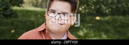 Fröhliches und echtes Kind mit Down-Syndrom bei lächelnder Brille im Park, Porträt, Banner Stockfoto