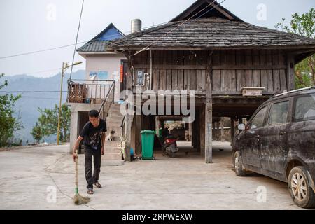 200426 -- MENGHAI, 26. April 2020 -- Ein Dorfbewohner reinigt den Boden im Dorf Manbansandui im Menghai County, südwestchinesische Provinz Yunnan, 12. April 2020. Weit entfernt in den Bergen des südwestlichen chinesischen Yunnan liegt der ehemalige Ort des armutsgeplagten Ortsteils Manbansandui, in dem 17 Haushalte der ethnischen Gruppe Lahu lebten. Unter Berücksichtigung der Lebensgewohnheiten und Gebräuche der Dorfbewohner wurde der Weiler 2009 in ein neues Gebiet umgesiedelt, das an seinen ursprünglichen Standort angrenzt, um die Lebensumwelt der Dorfbewohner zu verbessern und die Armut abzuschütteln. Zusätzlich zu den Infrastrukturprojekten Stockfoto