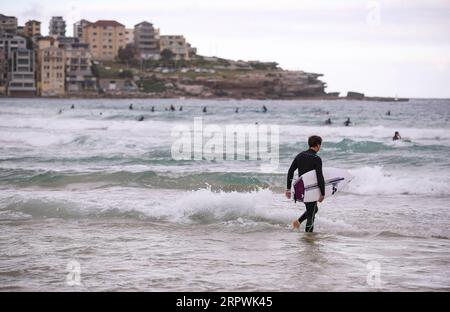 200428 -- SYDNEY, 28. April 2020 -- Ein Surfer spaziert am Bondi Beach in Sydney, Australien, am 28. April 2020 ins Wasser. Hunderte Aussies strömten am Dienstag ins Wasser, als der berühmte Bondi Beach für Surfer und Schwimmer wieder geöffnet wurde, nachdem er aufgrund von COVID-19 geschlossen wurde. AUSTRALIEN-SYDNEY-COVID-19-BEACH BaixXuefei PUBLICATIONxNOTxINxCHN Stockfoto