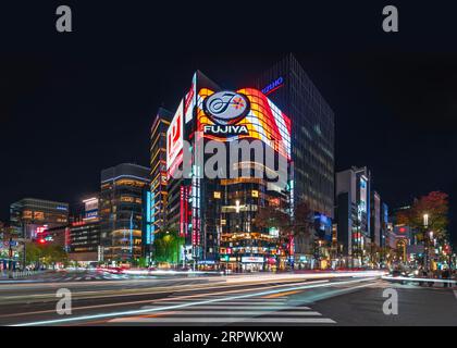 tokio, japan - November 29 2021: Die Straßen Sotobori und Harumi kreuzen sich am Ginza Scramble Crossing in der Innenstadt von Tokio, beleuchtet nachts durch das Neonzeichen o Stockfoto