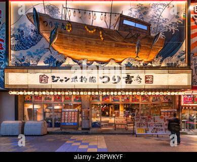 osaka, japan - 4. dezember 2022: Fisch- und Meeresfrüchte-Restaurant Jumbo Tsuribune Tsurikichi mit einem Fischerboot, das in Meereswellen segelt, die die große Welle o evozieren Stockfoto