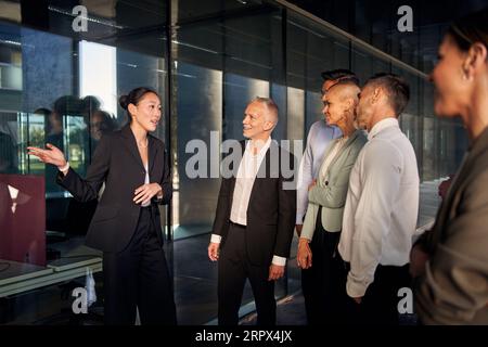 Teambesprechung verschiedener Experten, die der Chinease-Teamleiterin zuhören. Multirassische Parnerts. Stockfoto