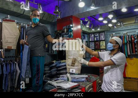 200511 -- DHAKA, 11. Mai 2020 Xinhua -- Ein Mann wählt Hosen in einem Geschäft in einem wiedereröffneten Markt in Dhaka, Bangladesch, am 11. Mai 2020. Am Montag wurden die wichtigsten Straßen und Straßen von Dhaka einen Tag nach der Wiedereröffnung von Geschäften und Märkten wieder belebt, allerdings auf begrenzter Basis, nachdem die Regierung dies angeordnet hatte. STR/Xinhua BANGLADESCH-DHAKA-COVID-19-EASING-LOCKDOWN PUBLICATIONxNOTxINxCHN Stockfoto