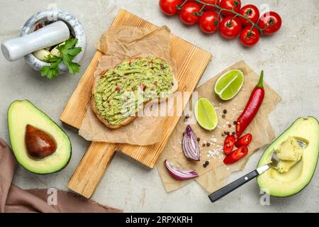 Köstliches Sandwich mit Guacamole und Zutaten auf hellgrauem Tisch, flach liegend Stockfoto