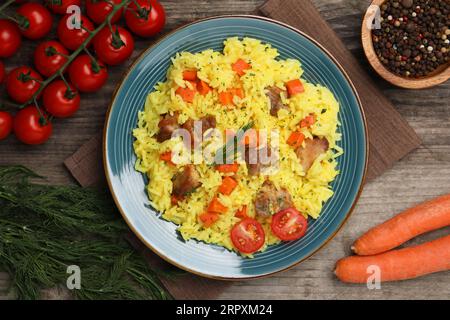 Köstliches Pilaf mit Fleisch und Zutaten auf Holztisch, flach gelegt Stockfoto