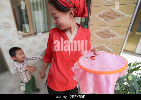 200531 -- LINXIA, 31. Mai 2020 -- Ma Semai interagiert mit ihrem Sohn während der Unterbrechung der Stickereien zu Hause in der Stadt Daban im Autonomen Kreis Dongxiang, Linxia Hui Autonome Präfektur der nordwestchinesischen Provinz Gansu, 30. Mai 2020. MA, 36 Jahre alt und der ethnischen Gruppe Dongxiang angehörend, ist eine der weiblichen Stickerinnen, die in einer traditionellen Stickereiwerkstatt arbeiten, die von der lokalen Regierung als Ansatz zur Armutsbekämpfung eingerichtet wurde. Der Workshop beschäftigte über 80 einheimische Frauen aus der Dongxiang-Ethnie, die gut in der Stickerei sind, und zog auch fast 200 einheimische Dorfbewohner an Stockfoto