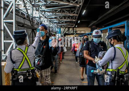 200601 -- MANILA, 1. Juni 2020 Xinhua -- Passagiere mit Gesichtsmasken warten in der Schlange, um ihre Körpertemperatur überprüfen zu lassen, bevor sie am ersten Tag in einen Zug einsteigen, als die COVID-19-Lockdown-Beschränkungen in Manila, den Philippinen, am 1. Juni 2020 weiter gelockert wurden. Der philippinische Präsident Rodrigo Duterte kündigte am 28. Mai an, ab dem 1. Juni weitere Lockdown-Beschränkungen in Metro Manila zu lockern, um die Wiedereröffnung von mehr Unternehmen und Verkehrsmitteln zu ermöglichen. Xinhua/Rouelle Umali PHILIPPINEN-MANILA-COVID-19-LOCKDOWN-EASING PUBLICATIONxNOTxINxCHN Stockfoto