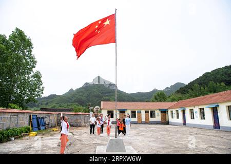 200603 -- LINGCHUAN, 3. Juni 2020 -- am 2. Juni 2020 findet im Mawuzhai Internat im Lingchuan County, der nordchinesischen Provinz Shanxi, Eine Flaggenhisserungszeremonie statt. Am 2. Juni kehrten Qin Chunlan, Qin Qiulan und Qin XingWang zur Schule zurück. Früh am Morgen stiegen sie auf das Dreirad ihres Vaters und eilten in die Grundschule des mehr als 10 Kilometer entfernten Mawuzhai-Internats. Die Familie der drei Kinder ist der einzige Haushalt im Dorf Nanbei im Lingchuan County, und die Grundschule ist die einzige Schule im Umkreis von dutzenden Kilometern. Es sind sieben Schüler drin Stockfoto