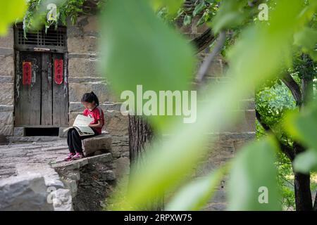 200603 -- LINGCHUAN, 3. Juni 2020 -- Qin Qiulan liest am 31. Mai 2020 ein Buch zu Hause im Dorf Nanbei im Lingchuan County in der nordchinesischen Provinz Shanxi. Am 2. Juni kehrten Qin Chunlan, Qin Qiulan und Qin XingWang zur Schule zurück. Früh am Morgen stiegen sie auf das Dreirad ihres Vaters und eilten in die Grundschule des mehr als 10 Kilometer entfernten Mawuzhai-Internats. Die Familie der drei Kinder ist der einzige Haushalt im Dorf Nanbei im Lingchuan County, und die Grundschule ist die einzige Schule im Umkreis von dutzenden Kilometern. Es gibt sieben Schüler in der Schule. F Stockfoto