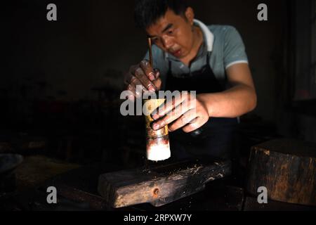 200603 -- SHEXIAN, 3. Juni 2020 -- Ein Arbeiter zerstreut Folienfetzen auf einen unfertigen Tintenstift in einer Werkstatt von Huizhou Tintenstift im Bezirk Shexian, ostchinesische Provinz Anhui, 21. Mai 2020. Inkstick wird häufig in der traditionellen chinesischen Malerei und Kalligraphie verwendet. Es wird in fester Form statt in flüssiger Form hergestellt und hält Generationen lang ohne Austrocknen. Zusammen mit Tintenbürste, Tintenstein und Papier ist Tintenstift einer der vier Schätze des Studiums in der traditionellen chinesischen Kultur. Der Huizhou Tintenstick ist ein hoch angesehener Tintenstift und hat seinen Namen von der historischen Region Huizhou, größtenteils in dem, was heute ist Stockfoto