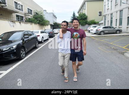 200612 -- ZHUJI, 12. Juni 2020 -- Jin Jiangwei L geht mit seinem Freund auf der Straße in der Stadt Zhuji, ostchinesische Provinz Zhejiang, 12. Juni 2020. Jin Jiangwei, ein 34-jähriger Dorfbewohner des Dorfes Leshan in der Stadt Zhuji, verlor seine Arme durch einen Unfall im Alter von fünf Jahren. Im Jahr 2016 eröffneten Jin Jiangwei und sein Bruder einen Online-Shop, in dem Jin für die Planung von Geschäften und den Kundenservice verantwortlich war. Nach jahrelangen Übungen kann Jin mit den Füßen genauso schnell tippen wie normale Menschen. Der Jahresumsatz des Stores hat in den letzten Jahren eine Million Yuan, etwa 141.288 US-Dollar, überschritten Stockfoto