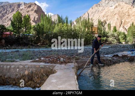 200618 -- TAXKORGAN, 18. Juni 2020 -- Amirjan Elim reinigt einen Wasserlauf in der Ortschaft Datung des autonomen Bezirks Taxkorgan Tadschik, nordwestchinesische Autonome Region Xinjiang Uygur, 14. Juni 2020. Das tief in einem Tal gelegene Datung Township ist von hoch aufragenden Bergen umgeben. Diese Berge sind für die Anwohner zu einem Hindernis für den Zugang zum nationalen Stromnetz geworden. Um das Stromversorgungsproblem zu lösen, organisierte die Stadt in den späten 1980er Jahren Dorfbewohner, um einen Graben entlang des Datung River zu bauen und führte einen Wasserkraftgenerator ein. Seit Jahren trifft das kleine Wasserkraftwerk kaum auf die örtliche po Stockfoto