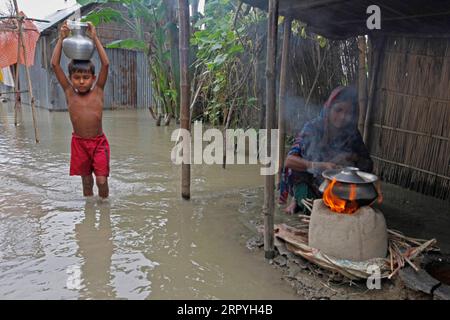 200702 -- JAMALPUR, 2. Juli 2020 Xinhua -- Eine Frau kocht auf einem Erdofen, während ein Junge am 2,2020. Juli in Jamalpur, Bangladesch, im Hochwasser steht. Überschwemmungen durch starke Regenfälle haben einige Teile Bangladeschs schwer getroffen. Xinhua BANGLADESH-JAMALPUR-FLUESSEN PUBLICATIONxNOTxINxCHN Stockfoto