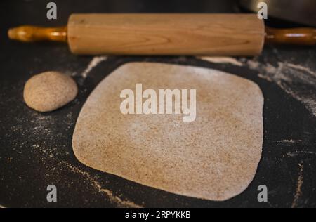 Ausgerollter Vollkornteig, Weizen, Korn mit Vintage-Rollnadel auf dem Tisch. Hausgemachter Bio-Teig. Gerollter Teig auf dem Tisch. Stockfoto