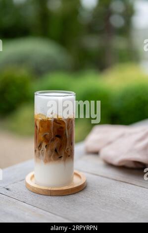 Nahaufnahme eines geeisten Macchiato auf einem Holztisch in einem wunderschönen Garten. Kalte Getränke, Getränke in der Café-Bar, Sommer Stockfoto