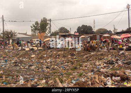 Waste-filled Valley in der Nähe der Main Road mit weggeworfenen Kunststoffverpackungen, stehendem Wasser und alten Reifen Stockfoto