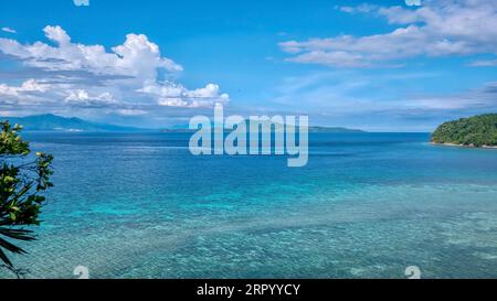 Tropische Korallen in flachem türkisfarbenem Wasser im Touristenresort Puerto Galera, Philippinen, mit Verde Island geradeaus und südlichem Luzon. Stockfoto