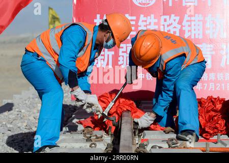 200721 -- RUOQIANG, 21. Juli 2020 -- Arbeiter legen die letzten Gleise auf der Golmud-Korla-Eisenbahnstrecke nahe dem Altun-Gebirge in der nordwestchinesischen autonomen Region Xinjiang Uygur, 21. Juli 2020. Die Verlegung von Gleisen für eine neue Strecke, die die autonome Region Xinjiang Uygur im Nordwesten Chinas mit der Provinz Qinghai und darüber hinaus verbindet, wurde am Dienstag abgeschlossen und ebnete den Weg für eine beschleunigte Entwicklung in der westlichen Region des Landes. Die 1.213,7 km lange Golmud-Korla-Bahn verbindet die Stadt Golmud in Qinghai mit der Stadt Korla in Xinjiang und soll noch in diesem Jahr in Betrieb genommen werden. CHINA-XINJI Stockfoto