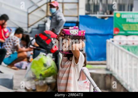 200729 -- PEKING, 29. Juli 2020 -- Ein Mädchen zieht einen Gesichtsschutz an, während die Leute auf kostenlose Reisen zurück in ihre Heimatstadt in einem Stadion in Manila, Philippinen, warten, 28. Juli 2020. XINHUA FOTOS DES TAGES RouellexUmali PUBLICATIONxNOTxINxCHN Stockfoto