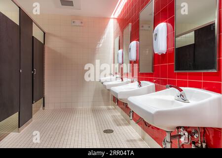 Öffentliche Toilette mit roten Fliesen und vier, Toiletten, Waschbecken Stockfoto