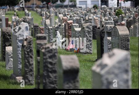 200730 -- NEW YORK, 30. Juli 2020 -- Eine US-Nationalflagge und Blumen sind auf einem Friedhof in New York, den Vereinigten Staaten, am 29. Juli 2020 zu sehen. COVID-19-Todesfälle in den USA haben die 150.000-Marke überschritten und erreichen am Mittwoch, 1935 GMT, um 15:35 Uhr Ortszeit 150.034, so das Center for Systems Science and Engineering an der Johns Hopkins University. U.S.-NEW YORK-COVID-19-CASES WangxYing PUBLICATIONxNOTxINxCHN Stockfoto