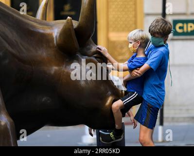 200730 -- NEW YORK, 30. Juli 2020 -- Kinder spielen auf dem Charging Bull in New York, USA, 29. Juli 2020. COVID-19-Todesfälle in den USA haben die 150.000-Marke überschritten und erreichen am Mittwoch, 1935 GMT, um 15:35 Uhr Ortszeit 150.034, so das Center for Systems Science and Engineering an der Johns Hopkins University. U.S.-NEW YORK-COVID-19-CASES WangxYing PUBLICATIONxNOTxINxCHN Stockfoto