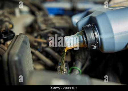 Nahaufnahme, bei der Öl in einen Fahrzeugmotor gegossen wird Stockfoto