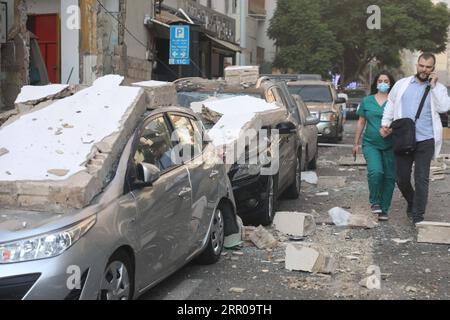 200804 -- BEIRUT, 4. Aug. 2020 Xinhua -- Menschen gehen an beschädigten Fahrzeugen nach der Explosion in Beirut, Libanon, 4. Aug. 2020 vorbei. Die beiden großen Explosionen, die am Dienstag die libanesische Hauptstadt Beirut erschütterten, ließen Dutzende Tote und Verletzte übrig, berichtete al-Jadeed TV-Sender. Xinhua/Bilal Jawich LIBANON-BEIRUT-RIESIGE EXPLOSIONEN PUBLICATIONxNOTxINxCHN Stockfoto