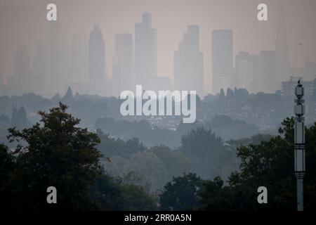 Wimbledon, London, Großbritannien. September 2023. Die Temperatur in London wird in diesem Jahr voraussichtlich die höchste sein, wobei ein milder und trüber Sonnenaufgang die Wolkenkratzer im Zentrum Londons und nebelige Vororte im Vordergrund verdeckt. Quelle: Malcolm Park/Alamy Live News Stockfoto