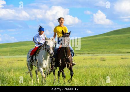 200809 -- XILIN GOL, 9. Aug. 2020 -- Xilinhua R und ein Freund reiten auf dem Baiyinxile Grasland in Xilinhot, Nordchinas Autonome Region Innere Mongolei, 4. Aug. 2020. Die Sommervationtion war Xilinhuas Lieblingszeit des Jahres. Um die Mittelschule zu besuchen, lebt die 14-Jährige die meiste Zeit bei ihren Großeltern in der Innenstadt von Xilinhot, getrennt von ihren Eltern, die eine Ranch auf der Baiyinxile-Weide betreiben. Daher bedeutet Sommer Entspannung und Wiedervereinigung zur siebten Klasse. Xilinhuas Vater Gangsuhe ist ein berühmter Reiter. Xilinhua lernte von ihm und beherrschte equ Stockfoto