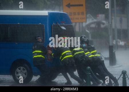 200819 -- MACAO, 19. August 2020 Xinhua -- Polizeibeamte schieben ein festgefahrenes Polizeifahrzeug in Macau, Südchina, 19. August 2020. Die Sonderverwaltungsregion Macau in China hat ihr Taifun-Signal von der höchsten Stufe 10 auf die Nummer 8 am Mittwoch um 7:30 Uhr Ortszeit herabgestuft, aber die tief gelegenen Gebiete in der Nähe der Küste wurden überflutet, da der Taifun Higos am Morgen in der Nachbarstadt Zhuhai landete. Das Macao Meteorological and Geophysical Bureau hatte sein Taifun-Signal am Mittwoch um 5:00 Uhr Ortszeit auf Platz 10 erhöht, bevor es später auf Platz 8 herabgestuft wurde. Der rote Sturm sur Stockfoto