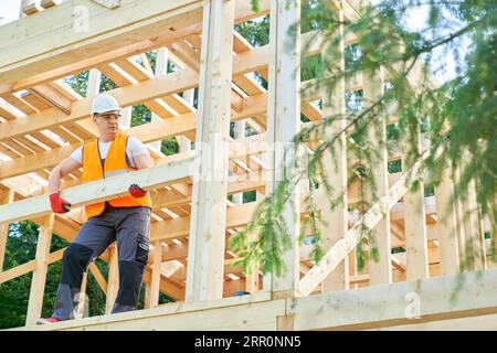 Männlicher Arbeiter, Handwerker, stehend, tragend, haltend, holzgolder im Freien aufsetzend. Stockfoto