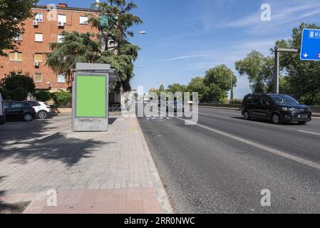 Eine Straße, die aus der Stadt führt, neben flachen Wohnhäusern und einer Bushaltestelle Stockfoto